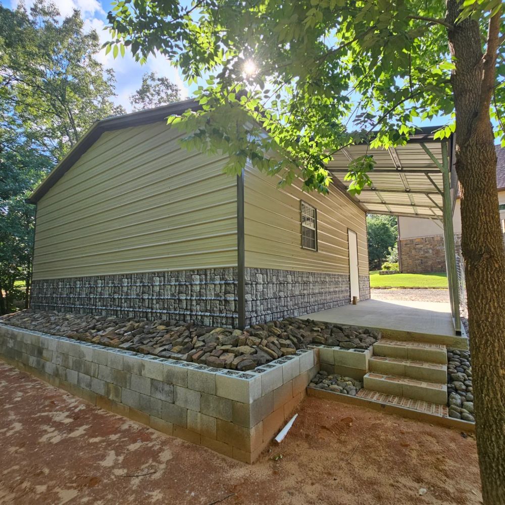 Yardmaster Creations metal building - tan building with stone skirting, lean-to carport and stone steps
