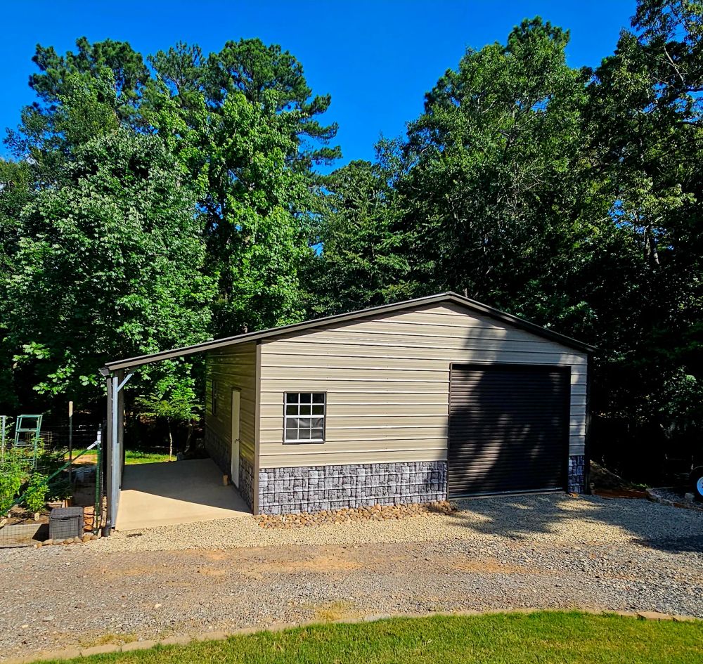 Yardmaster Creations metal garage - tan building with roll-up door, stone skirting and side carport